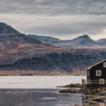 Una casa in riva al mare con i monti del fiordo di sfondo